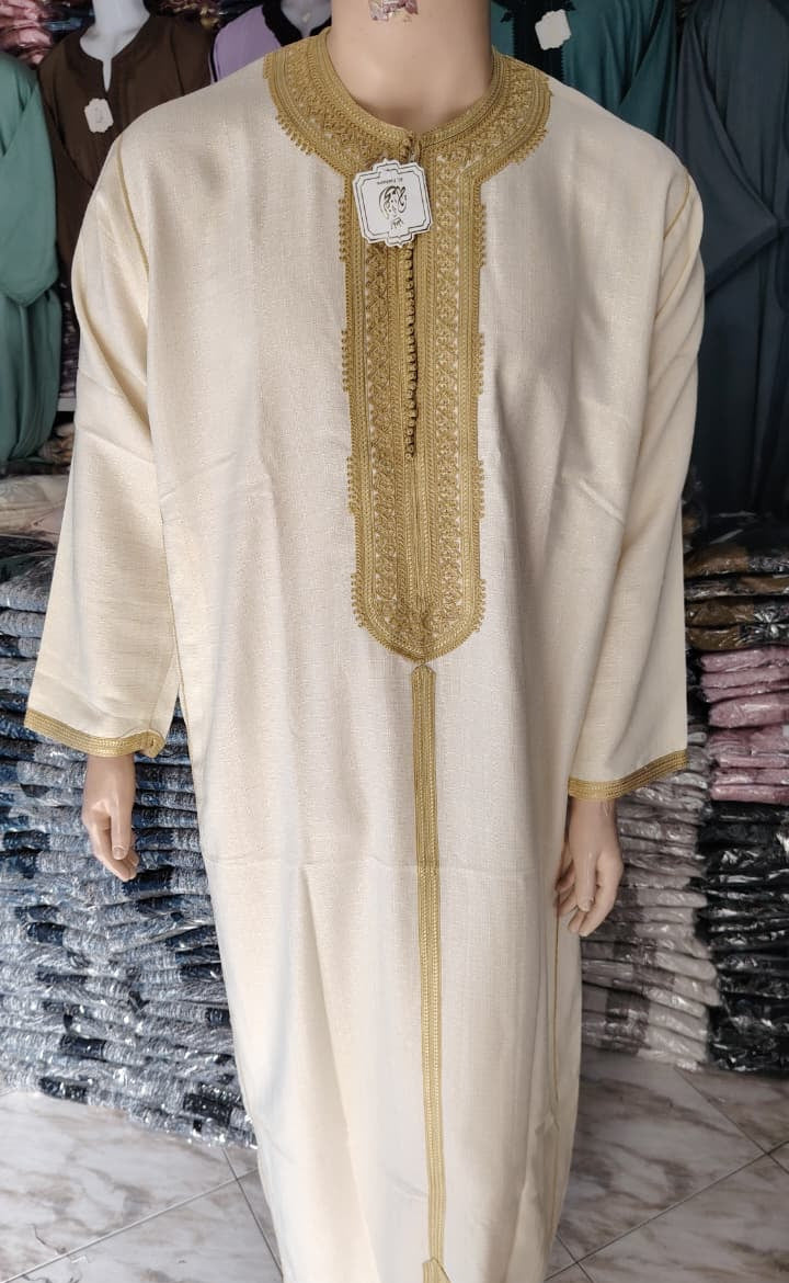 Real photograph of the Ivory and Gold embroidered Moroccan thobe, full length on a hanger in the shop in Morocco where my grandfather chooses the pieces.